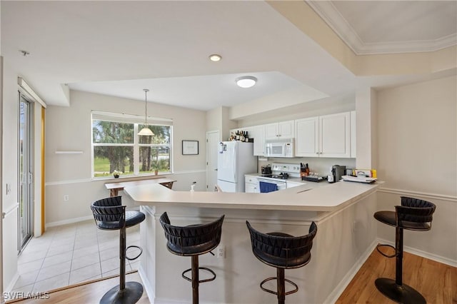 kitchen with a peninsula, white cabinetry, white appliances, pendant lighting, and light countertops