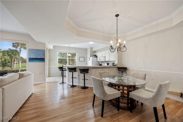 dining area featuring light wood finished floors, baseboards, a chandelier, and crown molding
