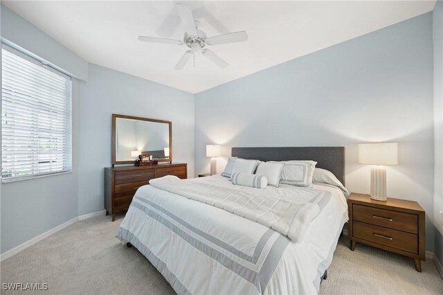 bedroom featuring light carpet, a ceiling fan, multiple windows, and baseboards
