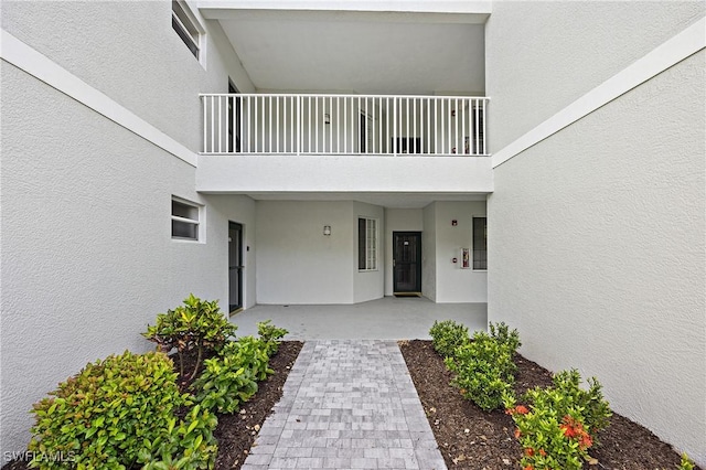 property entrance featuring a balcony and stucco siding