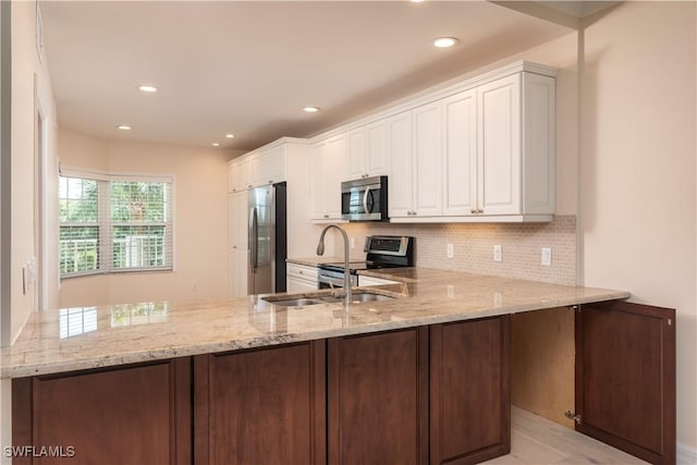 kitchen with a peninsula, appliances with stainless steel finishes, decorative backsplash, and white cabinets