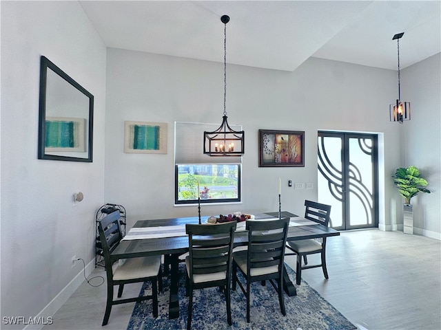 dining space with a high ceiling, hardwood / wood-style flooring, and an inviting chandelier