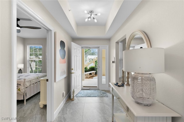 doorway to outside featuring ceiling fan and a raised ceiling