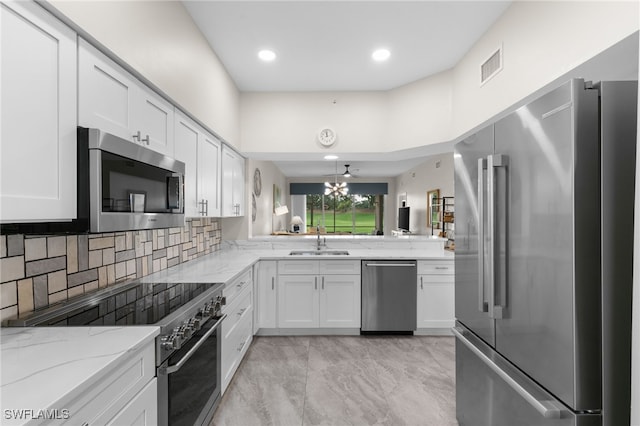 kitchen featuring light stone counters, white cabinets, sink, tasteful backsplash, and appliances with stainless steel finishes