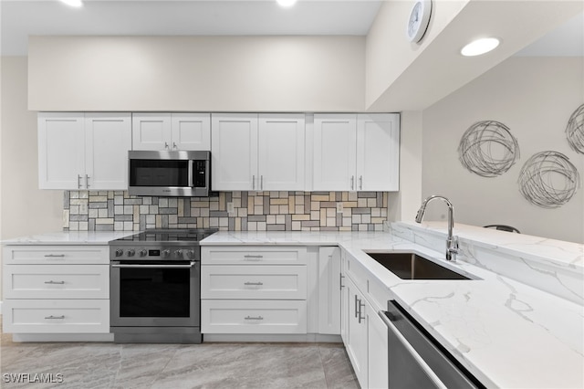 kitchen with tasteful backsplash, sink, white cabinets, stainless steel appliances, and light stone countertops