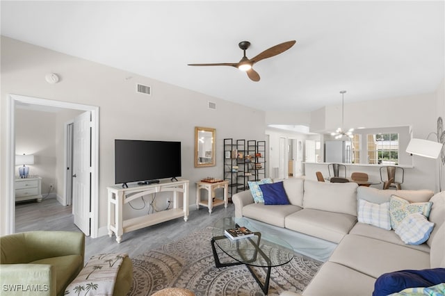 living room featuring ceiling fan with notable chandelier and hardwood / wood-style flooring