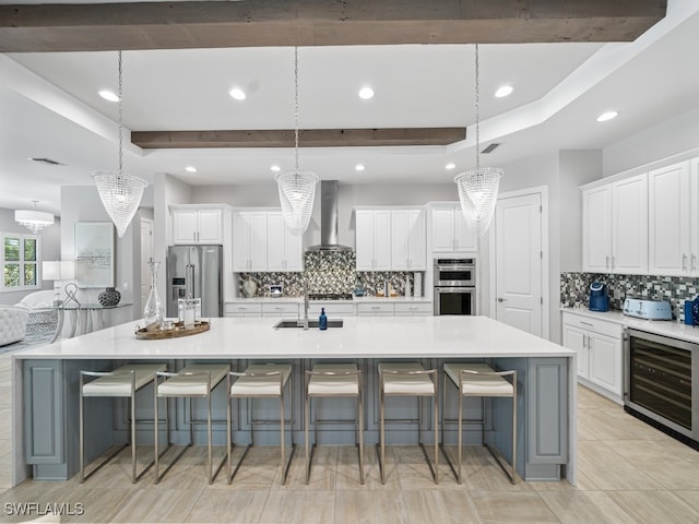 kitchen with a spacious island, stainless steel appliances, wall chimney exhaust hood, and hanging light fixtures