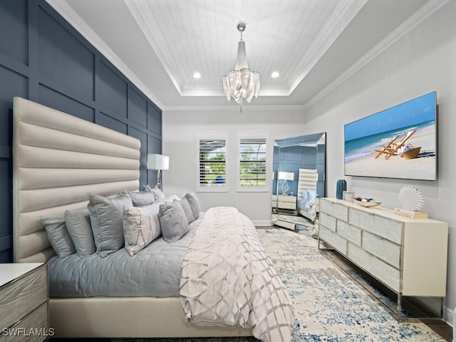 bedroom featuring a raised ceiling, ornamental molding, wood-type flooring, and an inviting chandelier