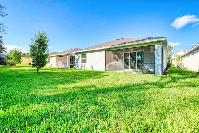 back of property featuring a sunroom and a yard