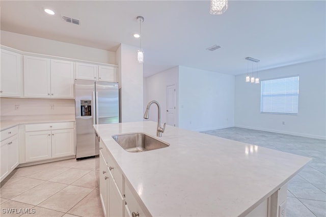 kitchen with stainless steel fridge with ice dispenser, sink, white cabinetry, a center island with sink, and decorative light fixtures