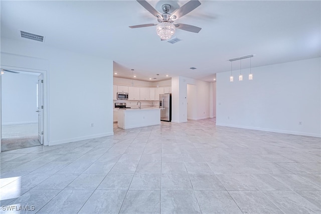 unfurnished living room with ceiling fan, light tile patterned floors, and sink