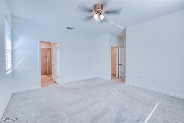 interior space with ceiling fan, light colored carpet, and ensuite bathroom