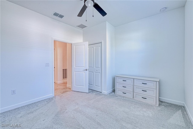 unfurnished bedroom featuring ceiling fan, a closet, and light carpet