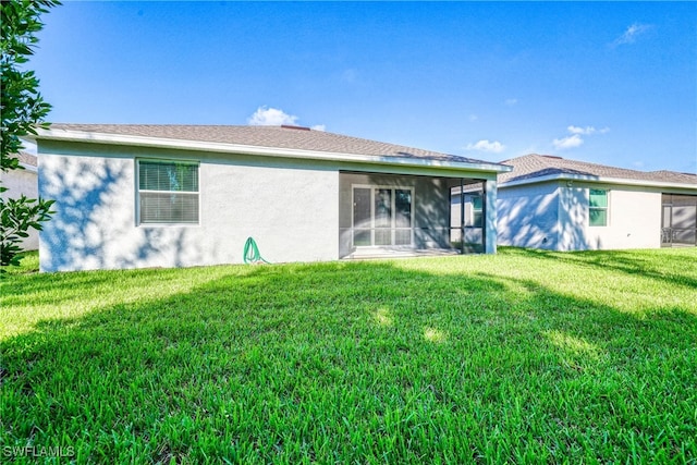 back of property featuring a sunroom and a lawn