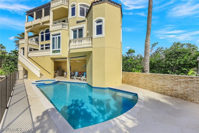 rear view of house featuring a patio area, a pool with connected hot tub, and stucco siding