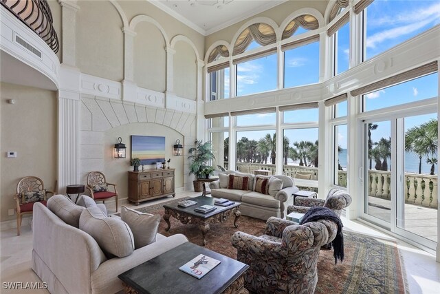 living room with ornamental molding, a towering ceiling, and baseboards