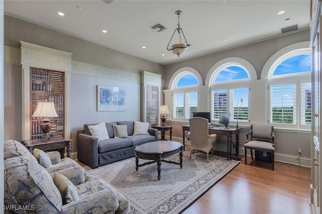 living room featuring baseboards, visible vents, ornamental molding, wood finished floors, and recessed lighting