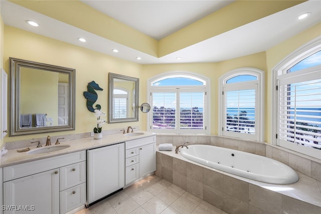 full bath with a whirlpool tub, double vanity, a sink, and recessed lighting