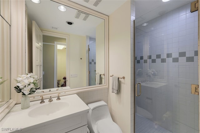 bathroom with toilet, vanity, visible vents, tile walls, and a stall shower