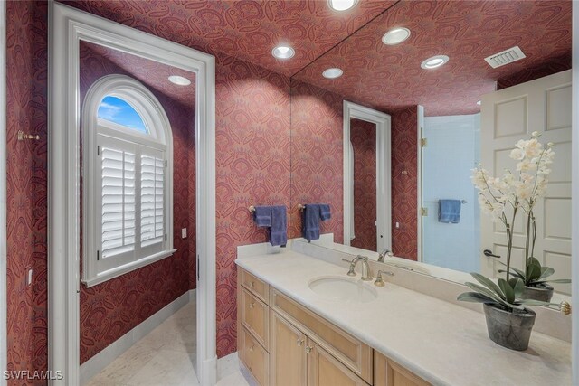 bathroom with recessed lighting, vanity, baseboards, visible vents, and wallpapered walls