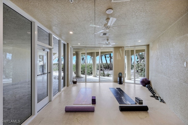 exercise room with a textured ceiling, a textured wall, visible vents, and floor to ceiling windows