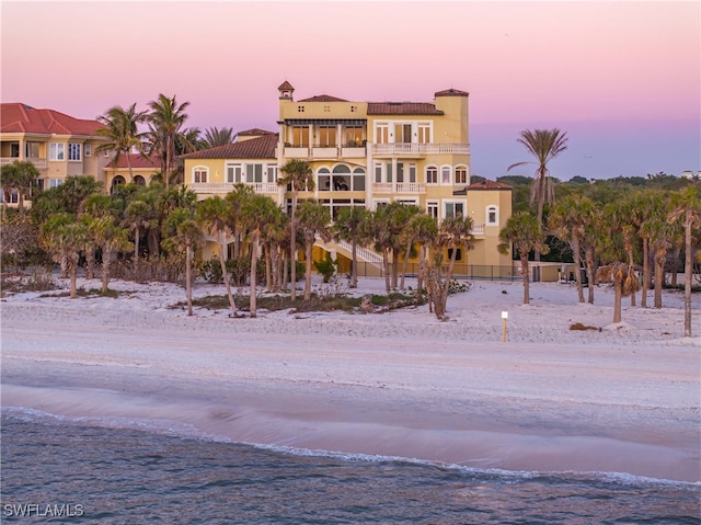 property at dusk featuring a beach view and a water view