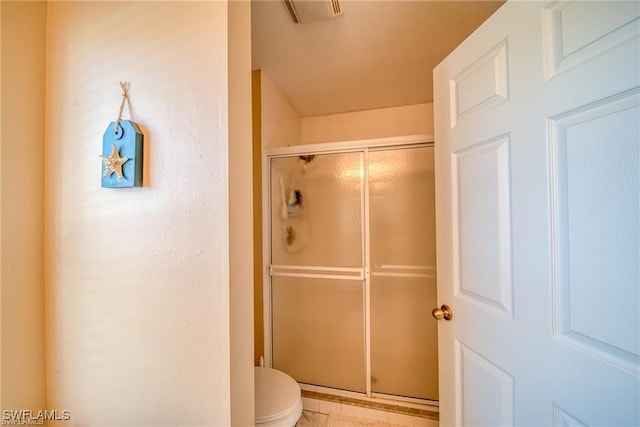 bathroom with a shower with door, toilet, and tile patterned floors