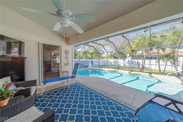 view of swimming pool featuring glass enclosure, ceiling fan, and a patio area