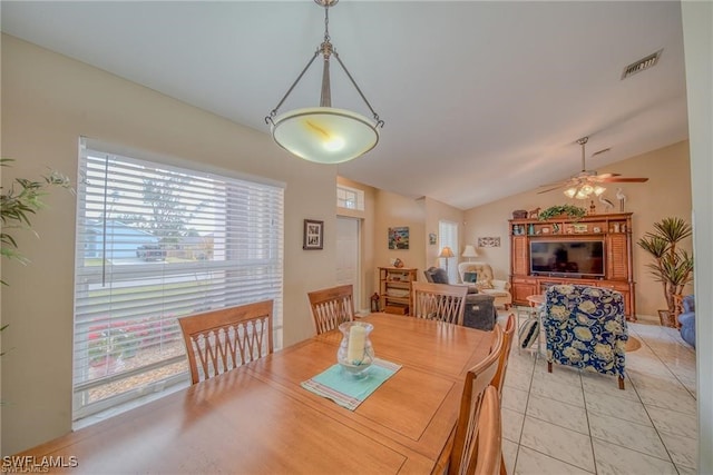 dining space with ceiling fan, light tile patterned flooring, and vaulted ceiling