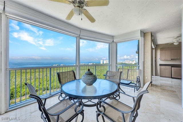 sunroom with a water view and ceiling fan