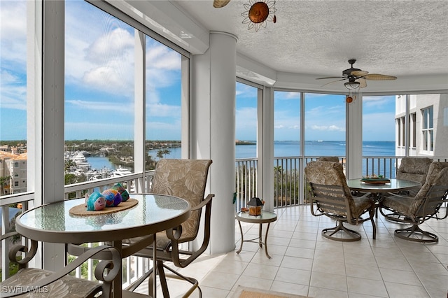 sunroom / solarium with ceiling fan and a water view