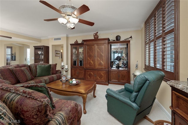 carpeted living room featuring ornamental molding and ceiling fan