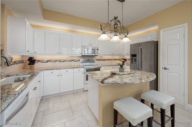 kitchen with stainless steel appliances, a center island, hanging light fixtures, sink, and white cabinetry