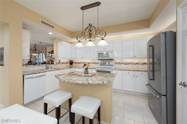 kitchen featuring stainless steel appliances, white cabinets, hanging light fixtures, a breakfast bar area, and a kitchen island