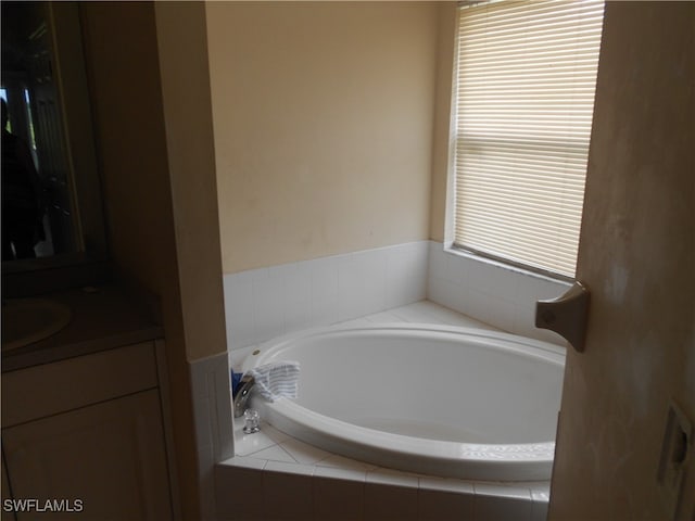 bathroom with vanity and tiled tub