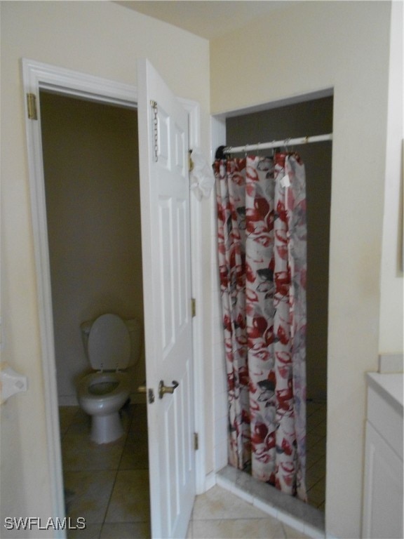 bathroom featuring vanity, toilet, walk in shower, and tile patterned flooring