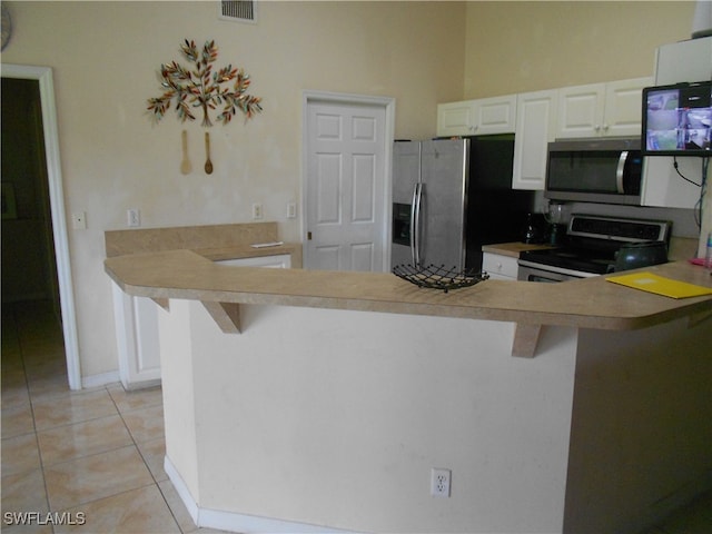 kitchen with a breakfast bar, white cabinets, kitchen peninsula, and stainless steel appliances