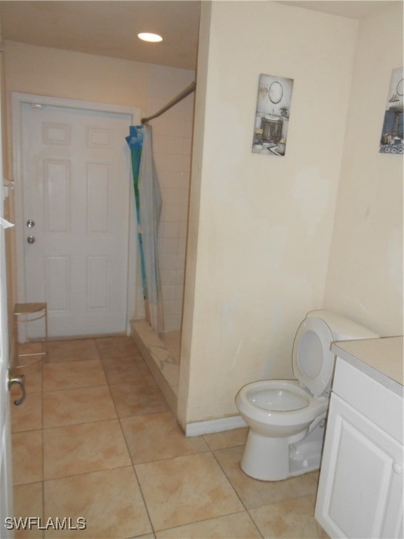 bathroom with toilet, a shower with curtain, vanity, and tile patterned floors