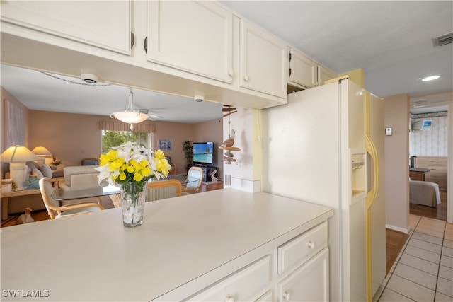 kitchen featuring white fridge with ice dispenser, white cabinetry, and light tile patterned floors