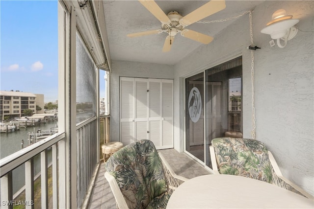 unfurnished sunroom with ceiling fan and a water view