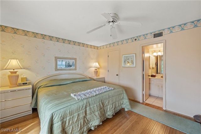 bedroom featuring ceiling fan, light hardwood / wood-style flooring, and ensuite bath