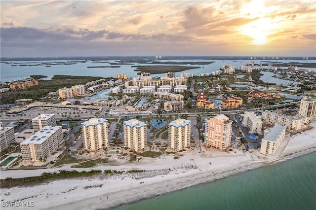 aerial view at dusk with a water view and a beach view