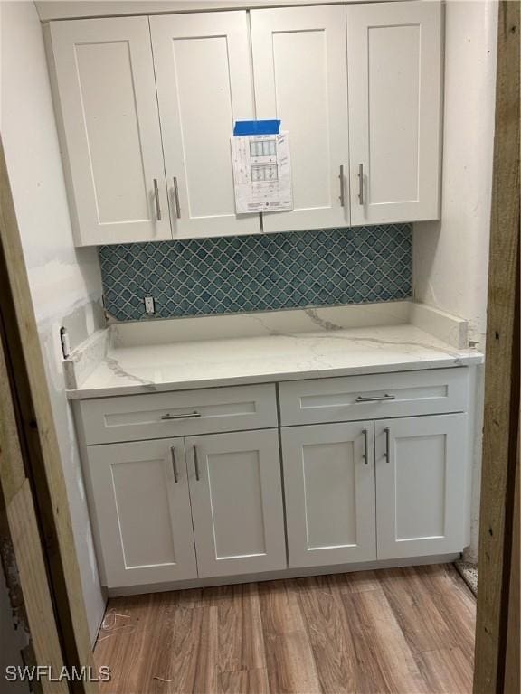 kitchen featuring tasteful backsplash, light stone countertops, and light wood-type flooring