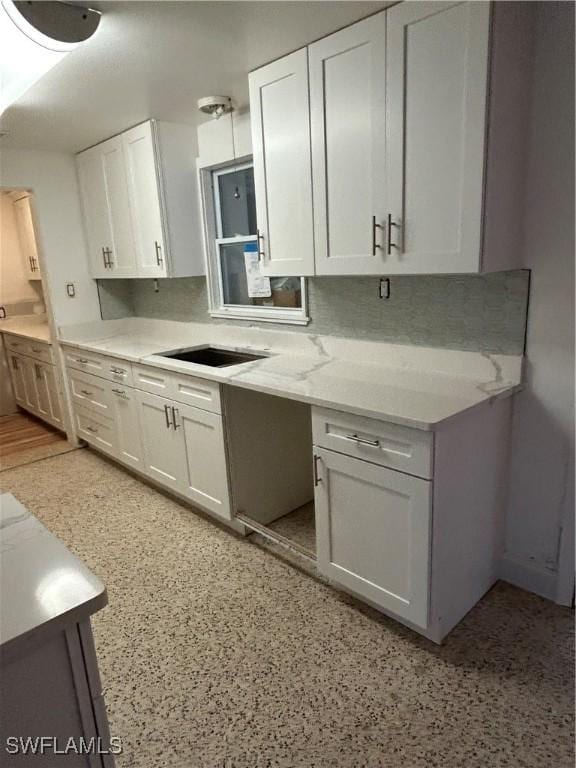 kitchen featuring sink, light stone countertops, and white cabinets