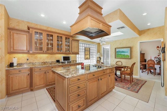 kitchen with a kitchen island, light stone counters, ceiling fan, black electric stovetop, and light tile patterned floors