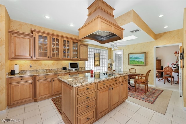 kitchen featuring a ceiling fan, visible vents, a center island, light stone counters, and black electric cooktop
