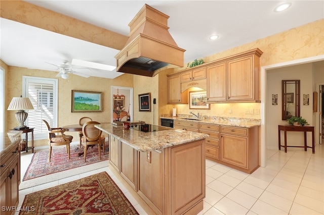 kitchen featuring a sink, ceiling fan, black electric stovetop, wallpapered walls, and light stone counters