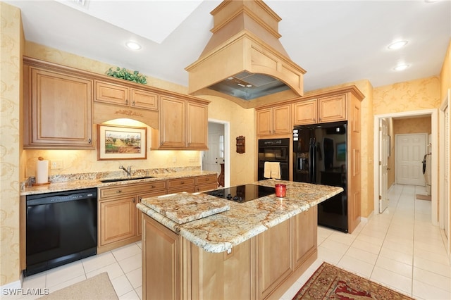 kitchen featuring light stone countertops, black appliances, a kitchen island, a sink, and premium range hood