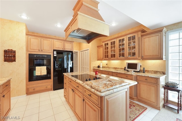 kitchen featuring custom exhaust hood, light tile patterned floors, glass insert cabinets, light stone countertops, and black appliances