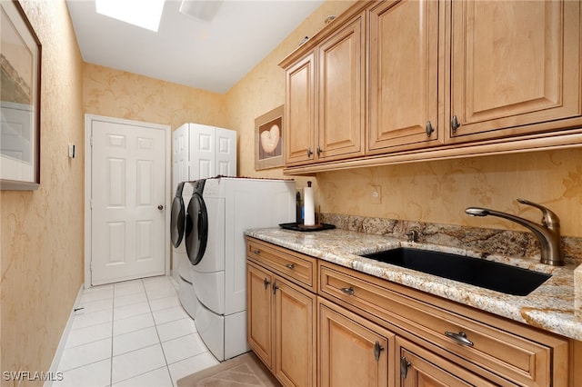 clothes washing area featuring light tile patterned floors, cabinets, sink, and washing machine and clothes dryer